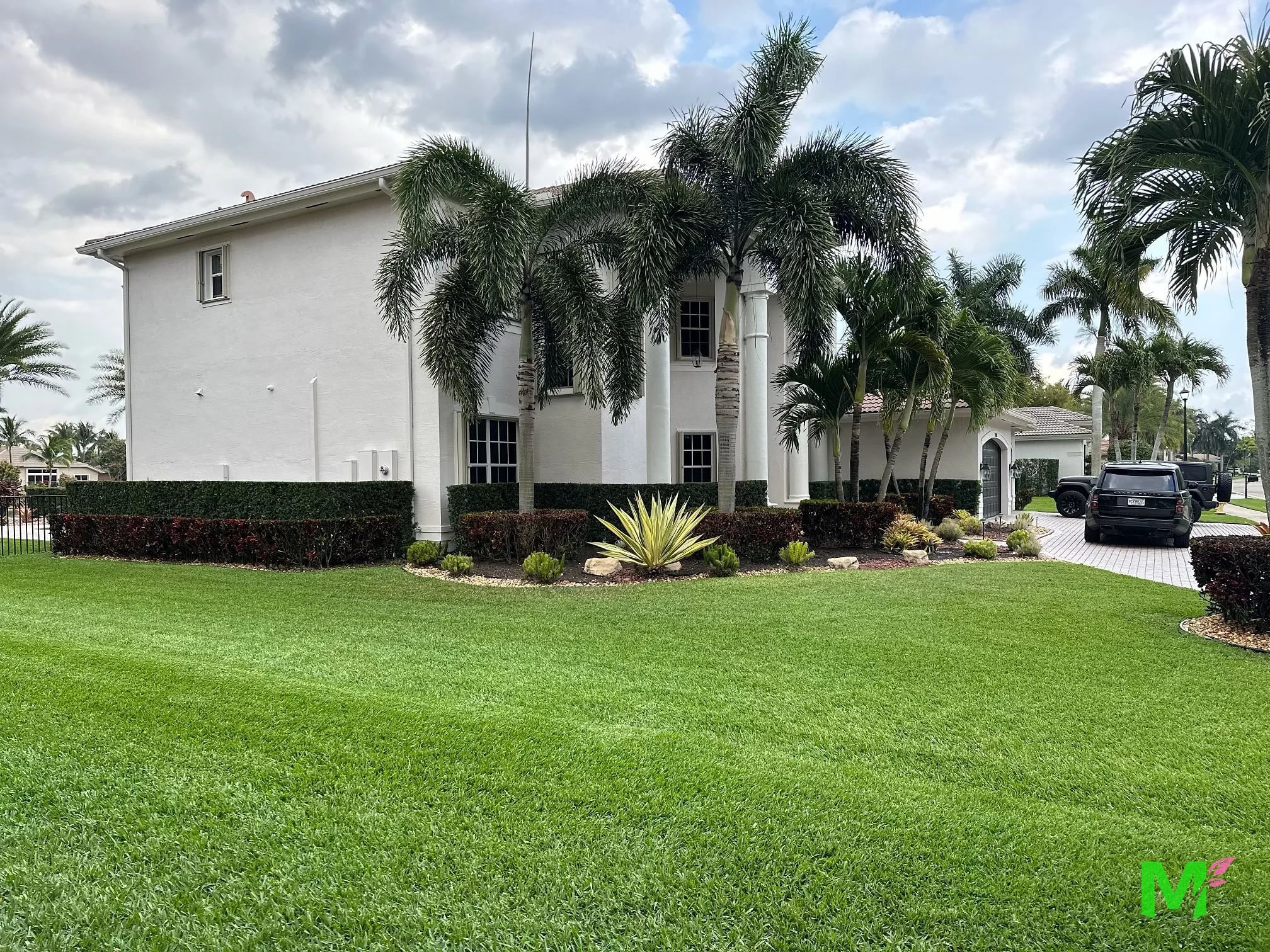 Two-story home with clustered palms, clipped hedges and a manicured front lawn