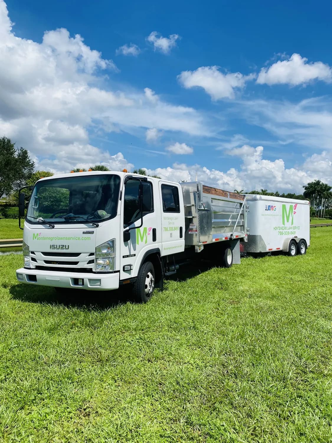 Montenegro Lawn Service dump truck and branded enclosed trailer on maintained turf