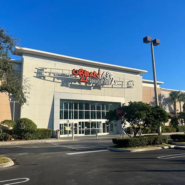 Commercial plaza entrance with maintained hedges and shade trees